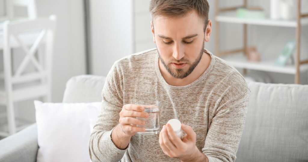 Man - taking - meds - holding a glass of water