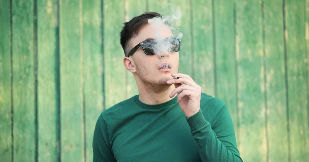 Young man smoking a joint with the best sativa strain