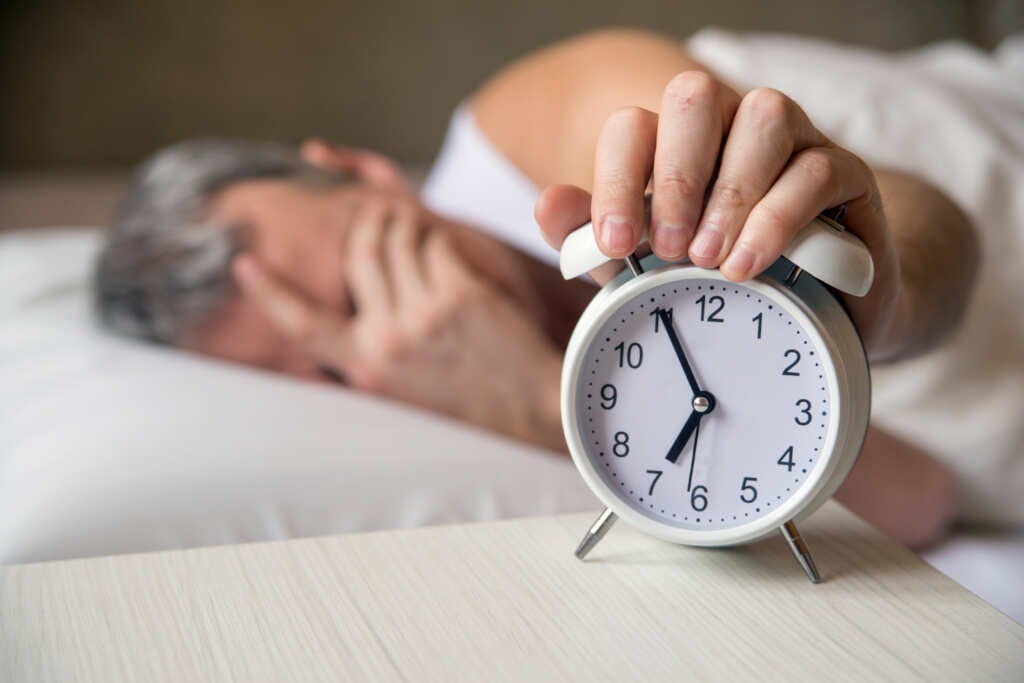 man-lying-bed-turning-off-alarm-clock-morning-7am-attractive-man-sleeping-his-bedroom-annoyed-man-being-awakened-by-alarm-clock-his-bedroom- strain-Indica- sleeping