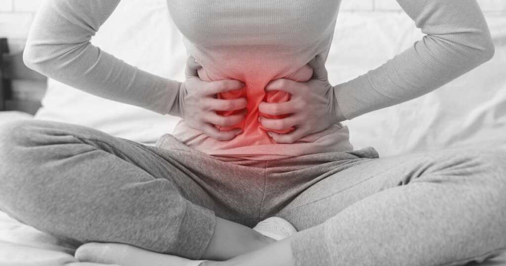 Woman experiencing menstrual cramp, holding her stomach.