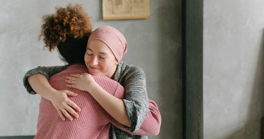Woman with cancer - Chemotherapy - hugging other woman - smiling with hope and nausea relief