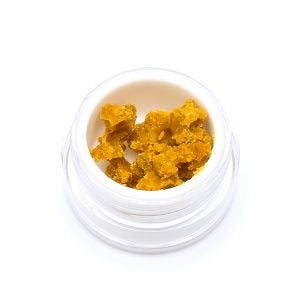 Budder from Seven Star. Dark orange wax-like substance in a white plastic container. Product is sitting on a white background.