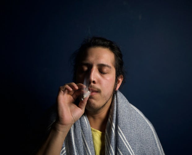 Young middle eastern man smoking a joint. His eyes are closed and he seems to be in a state of relaxation.