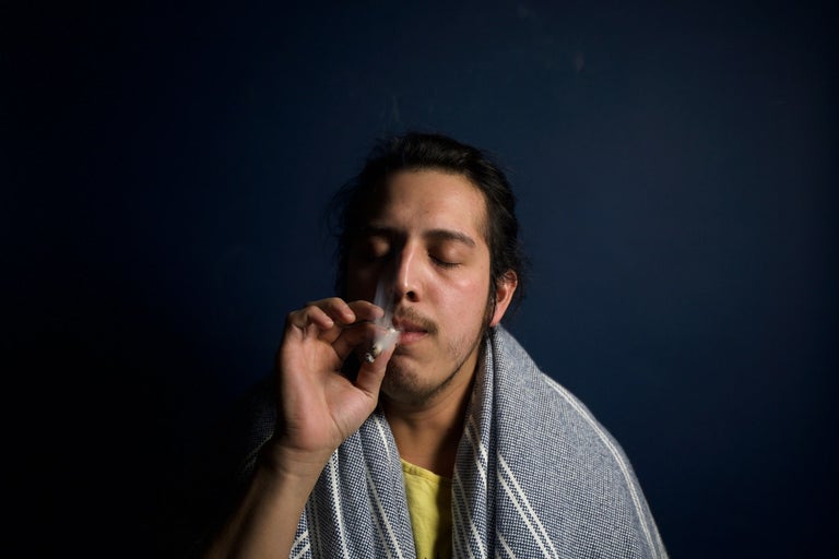 Young middle eastern man smoking a joint. His eyes are closed and he seems to be in a state of relaxation.