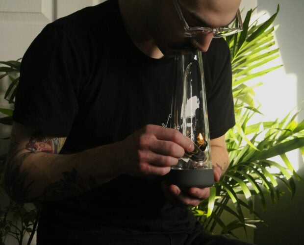 Young man smoking from a bong.