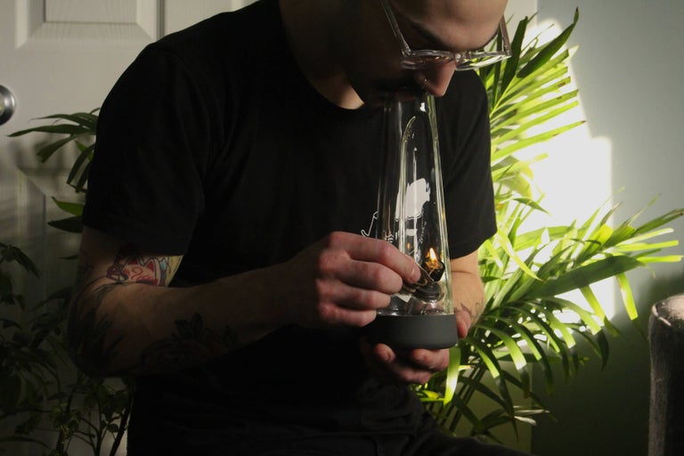 Young man smoking from a bong.