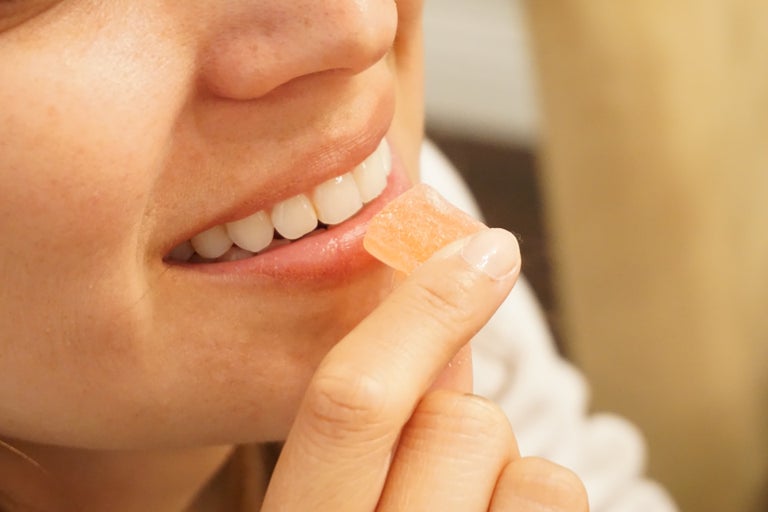 Woman with edible in her hand putting it iinto her mouth.