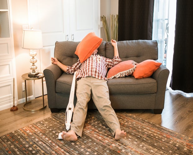 Middle-aged man sleeping on couch after smoking too much weed. He is in deep sleep with his arms and legs spread out wide with a pillow on his face.