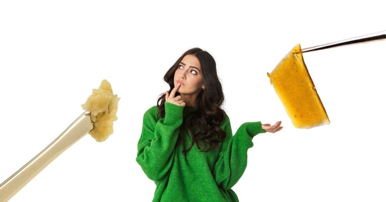 Girl contemplating between shatter and live rosin. Live rosin is on her left while shatter is on her right.