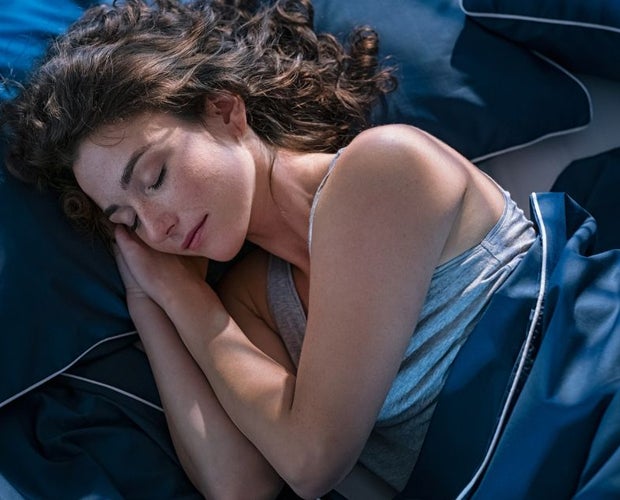 Young woman in deep sleep in a blue bed.
