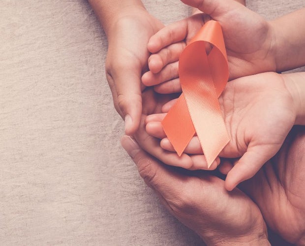 3 pair of hands stacked over each other, holding a ribbon for multiple sclerosis in unison.