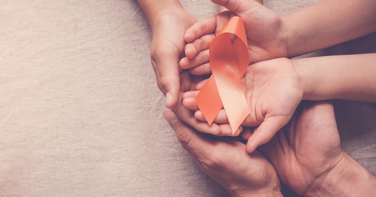 3 pair of hands stacked over each other, holding a ribbon for multiple sclerosis in unison.