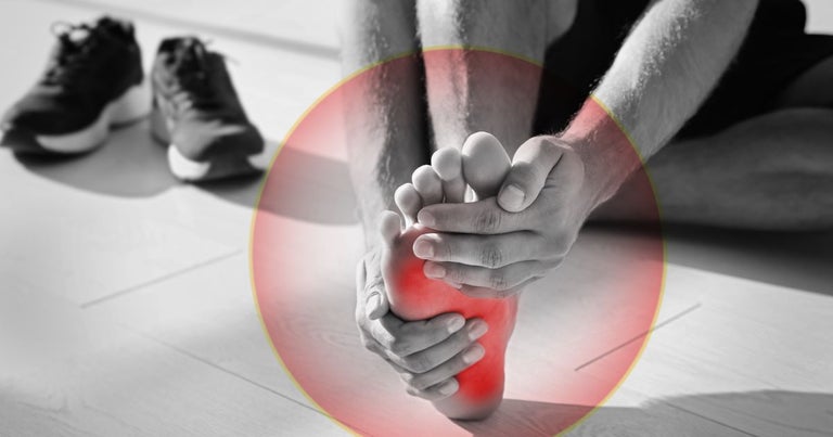 Man affected by muscle spasms. He is holding his foot with both hands while the area affected is highlighted in red.