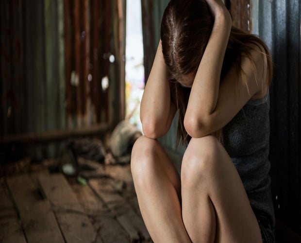 Young woman experiencing ptsd. Holding her head with both of her hands.