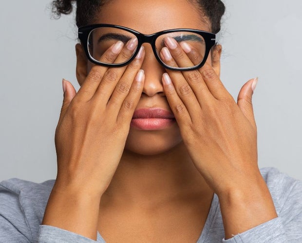 Young woman holding her eyes with both hands due to glaucoma.