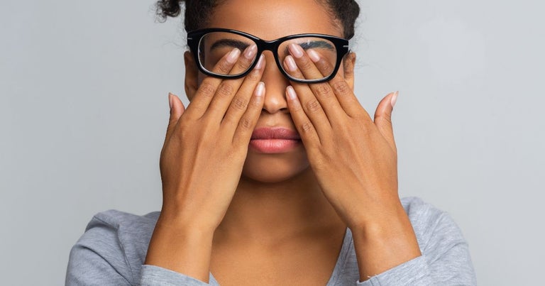 Young woman holding her eyes with both hands due to glaucoma.