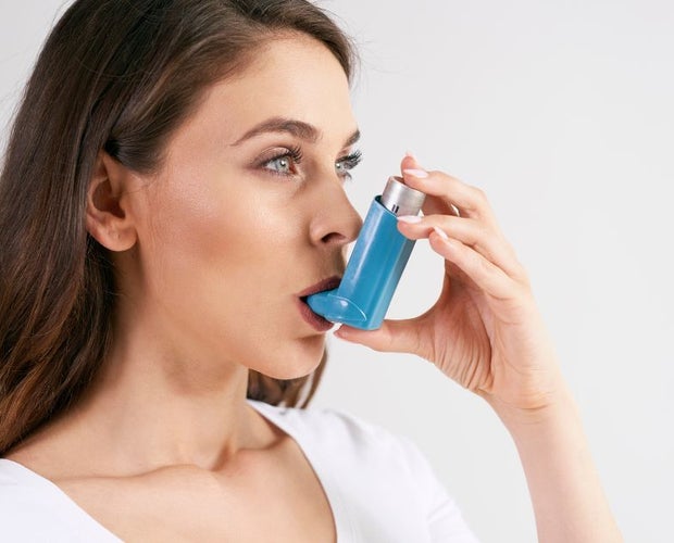 Woman with asthma. She is holding an epi pen to her mouth.