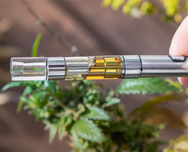 A sleek, modern shatter pen or dab pen next to a cannabis leaf