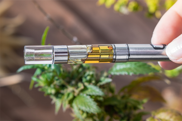 A sleek, modern shatter pen or dab pen next to a cannabis leaf