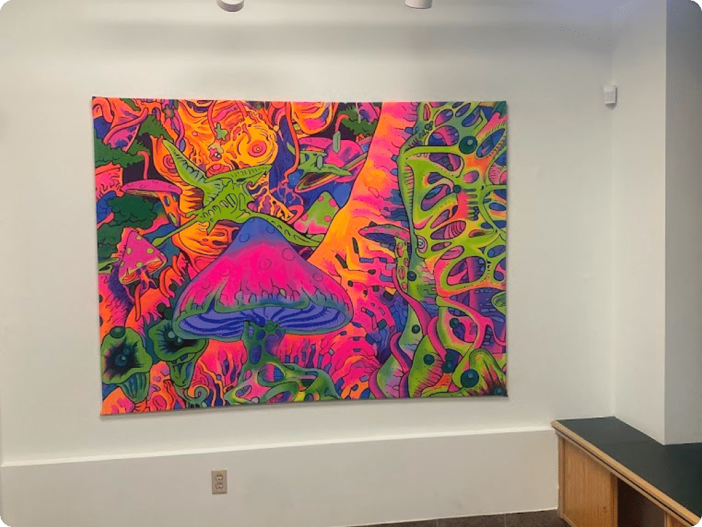 Abstract psychedelic painting as a decor element at Four Winds Drive Funguyz dispensary, next to products inside the store