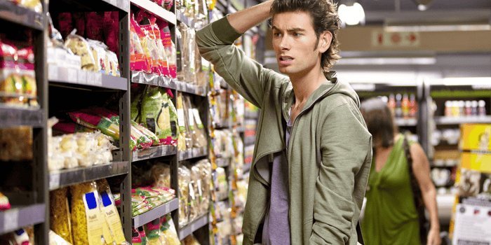 Confused young man at the grocery store choosing products