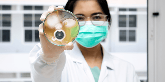 woman with mask holding mold in glass container