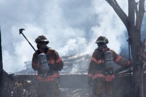 2 firefighters standing after extinguishing a large fire