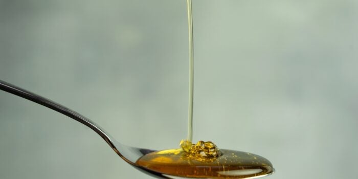 Honey oil poured on spoon.