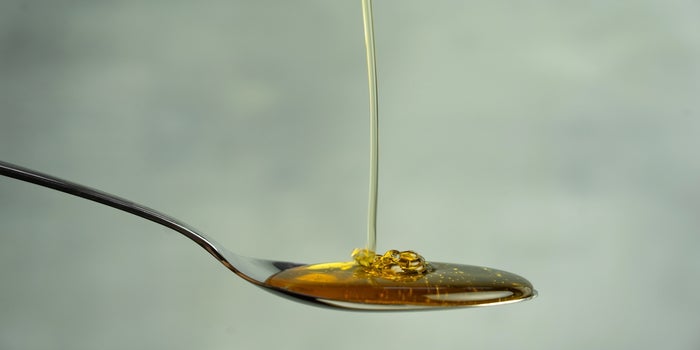 Honey oil poured on spoon.