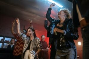 A picture of a group of men and woman dancing in a bar with one hand in the air.