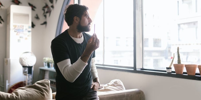 A picture of a young man holding a joint and contemplating what to do.