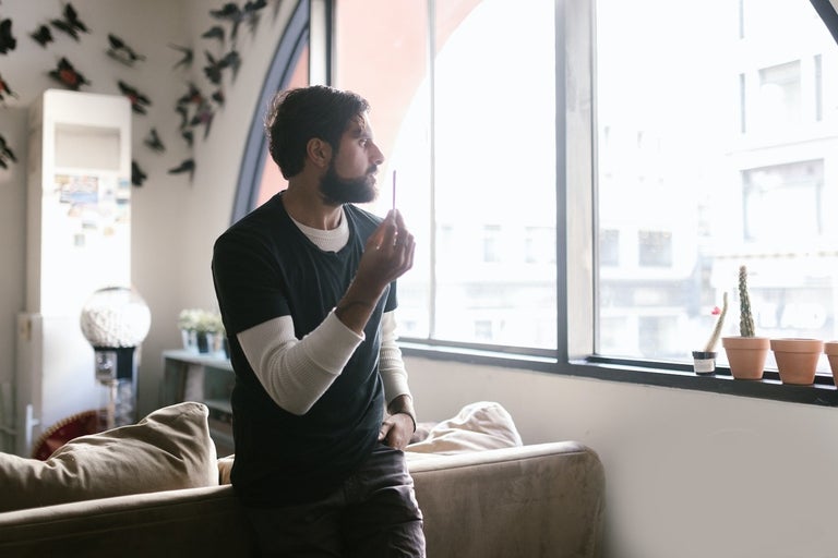 A picture of a young man holding a joint and contemplating what to do.