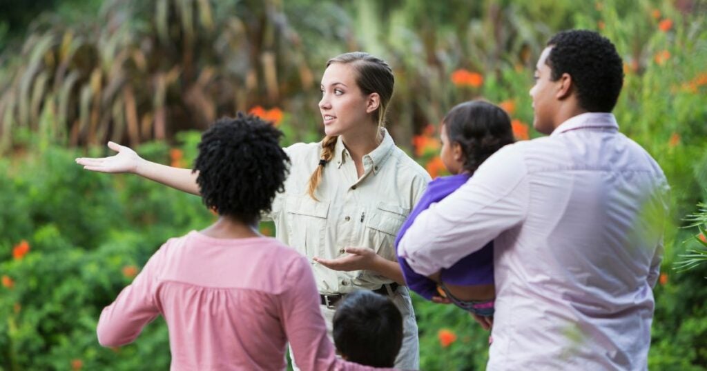 Female tour guide showing a family around a garden.