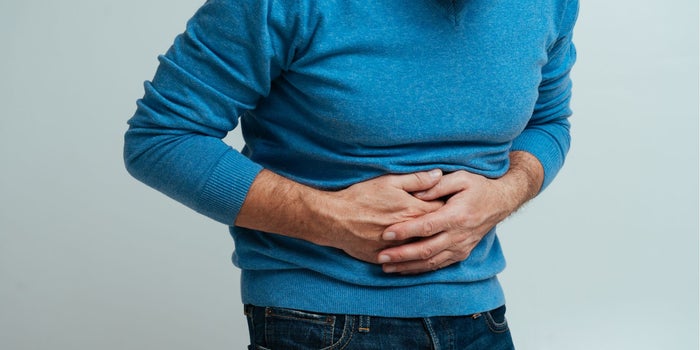 Elderly man suffering from IBD disease. He is holding his stomach with both hands.