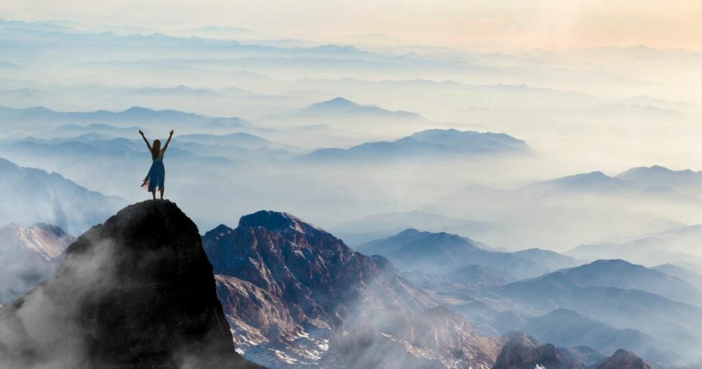 Young woman standing on the top of the mountain free from pain.