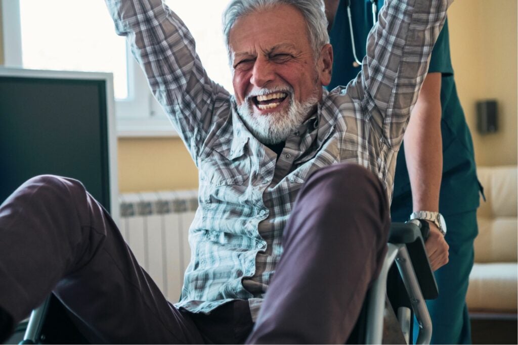 Patient in a wheel chair with his arms up in the air.
