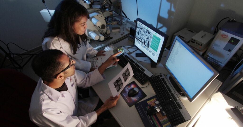 Two scientists in a room researching using a computer.