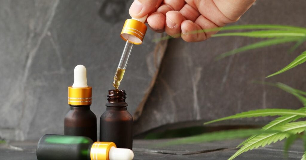 CBD oil in a bottle. The person is using a syringe to extract the contents.