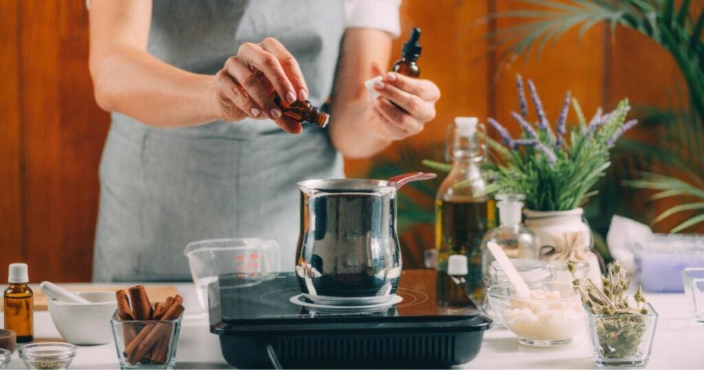 Honey oil vs cherry oil article featured image. A woman in an apron creating her own beverage. She is pouring the contents of thc oil in the pot.