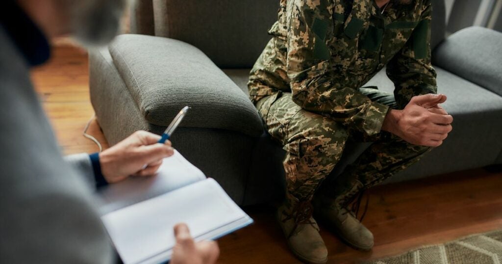 Military man suffering from PTSD. He is sitting on a couch talking to his counsellor.