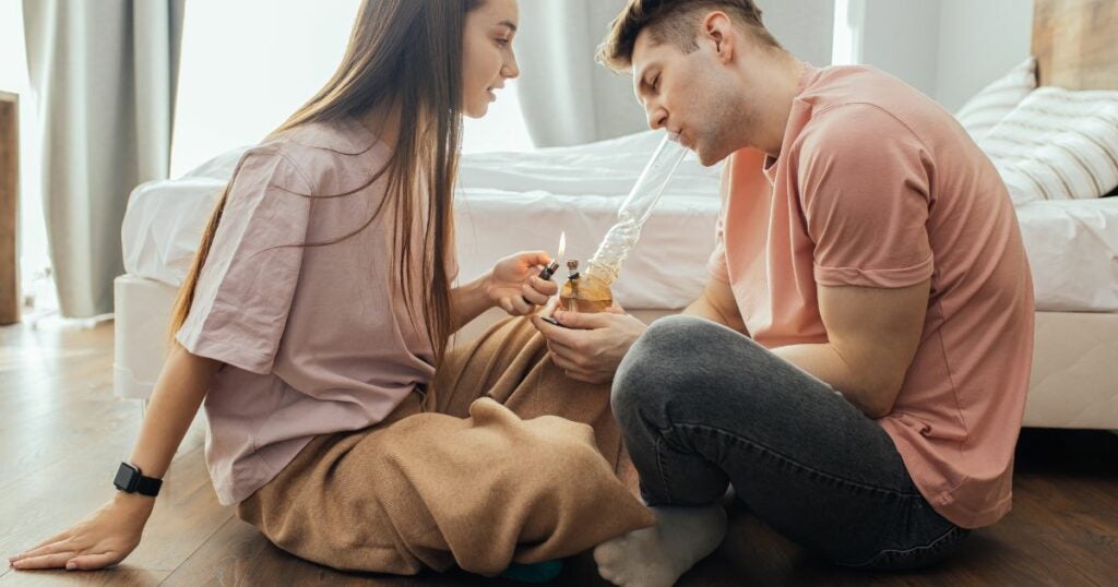 Couple smoking from a bong.