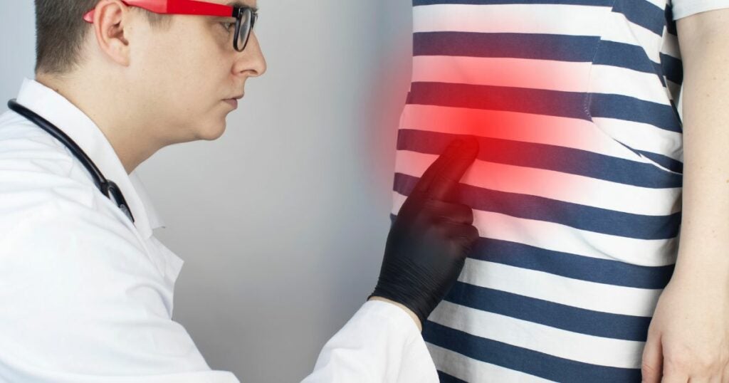 Patient affected by Crohn's disease. A doctor is checking out her stomach while the stomach is highlighted red to show the area that is affected.