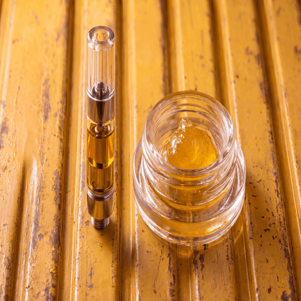 Live resin vape cartridge beside a jar of live resin concentrate
