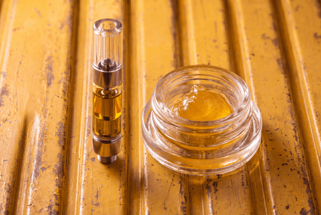 Live resin vape cartridge beside a jar of live resin concentrate