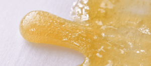 Hash rosin on a white background. Orange liquid-like substance.