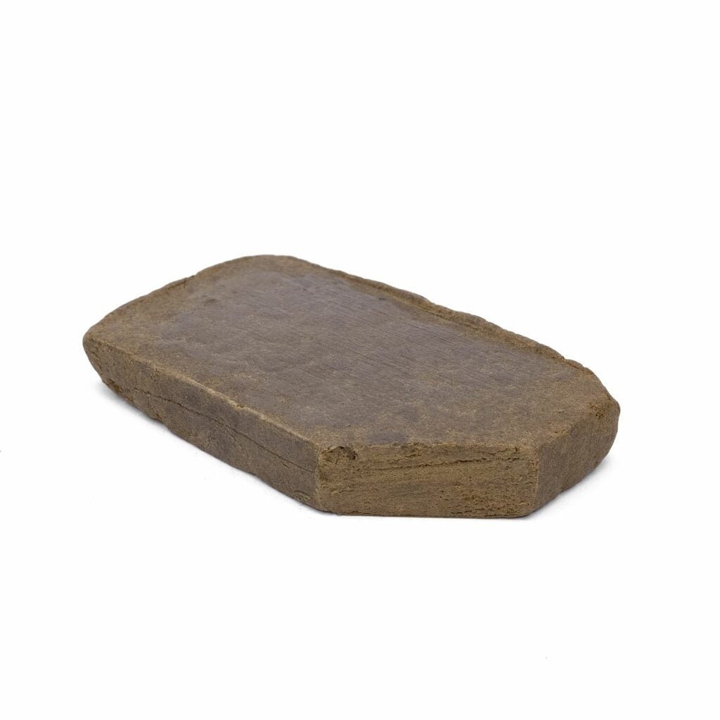 Imported Moroccan hash. Brown clay-like object sits on a whit surface.