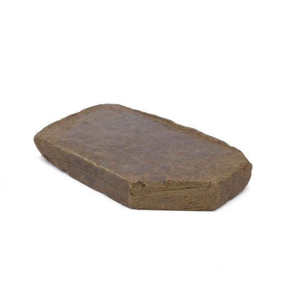 Imported Moroccan hash. Brown clay-like object sits on a whit surface.