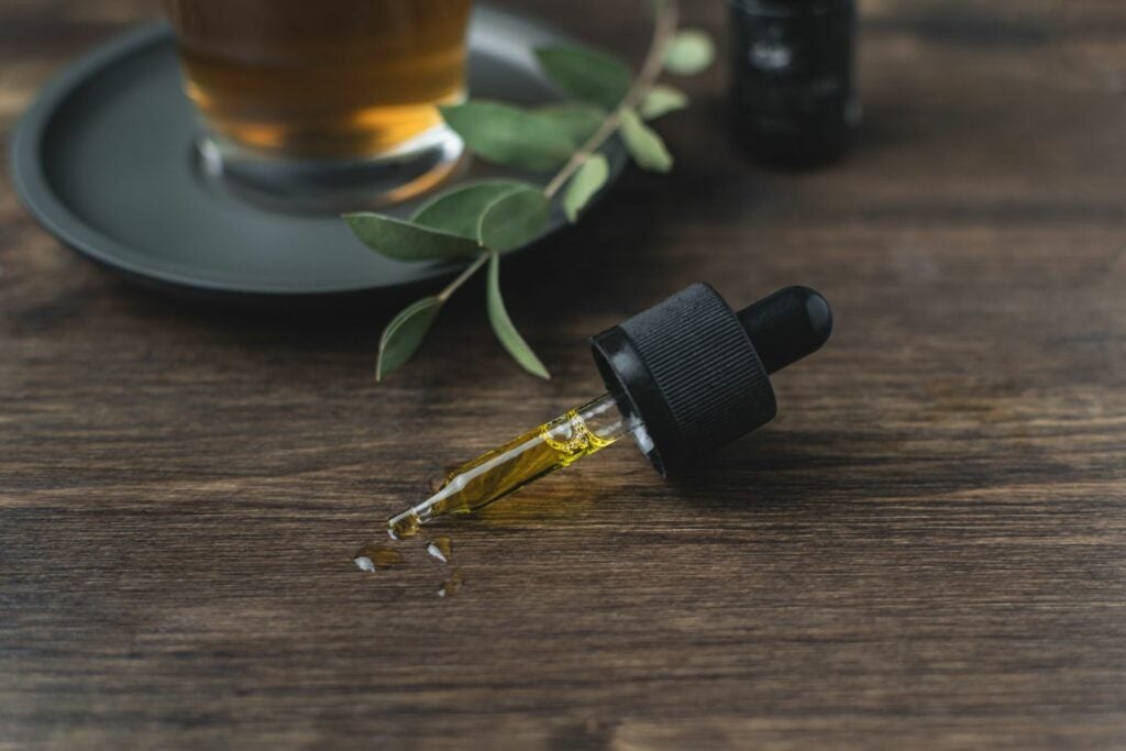 THC Oil syringe on the table with a little bit of oil leaking onto the table.