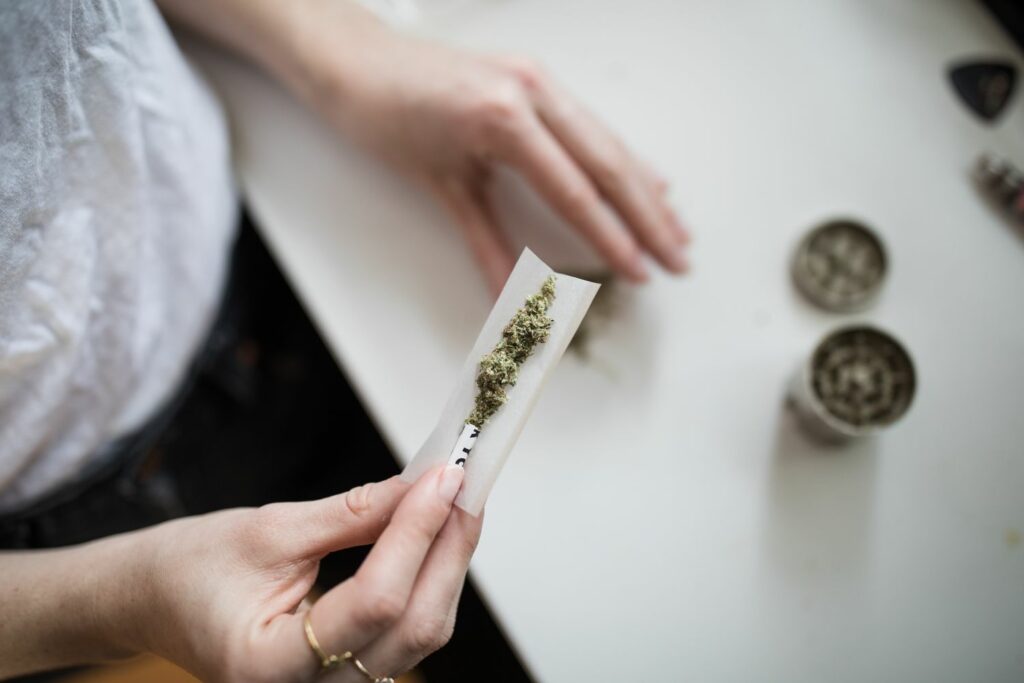 Rolling a joint after a tooth extraction. Woman in white clothing rolling using a rolling paper, weed, and filter.