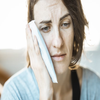 Middle aged white woman holding an ice pack on her cheek to soothe the pain from removing a tooth.